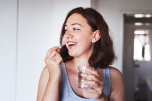 woman taking medication for her mental health and smiling