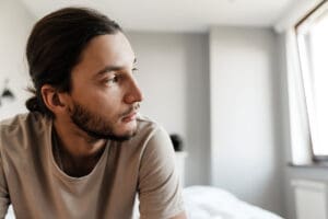 Young man in depression sitting on bed at home